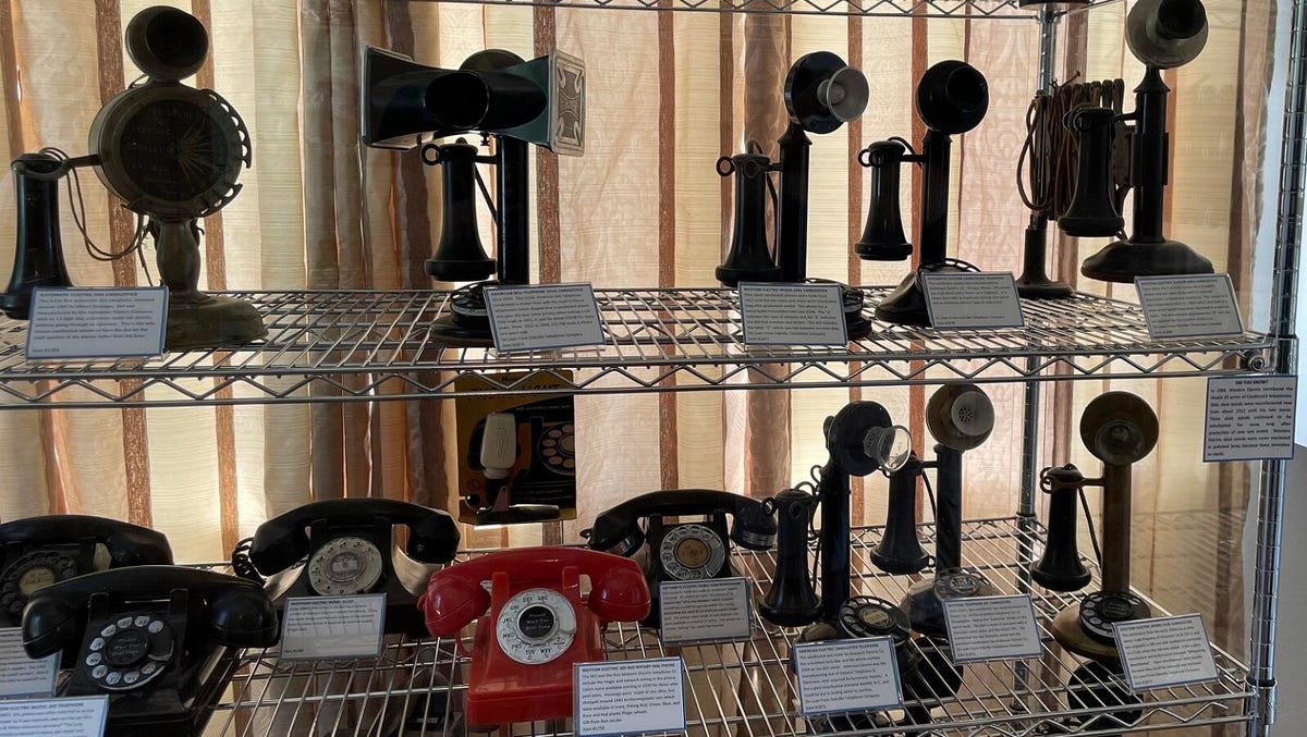 Rows of old phones, including "candlestick" models with upright mouthpieces and movable earpieces.